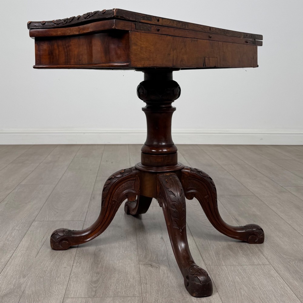 A 19th-century Victorian tea table in figured walnut, showcasing a carved rim, deep apron, turned pedestal, and four acanthus-carved scroll legs. View IV