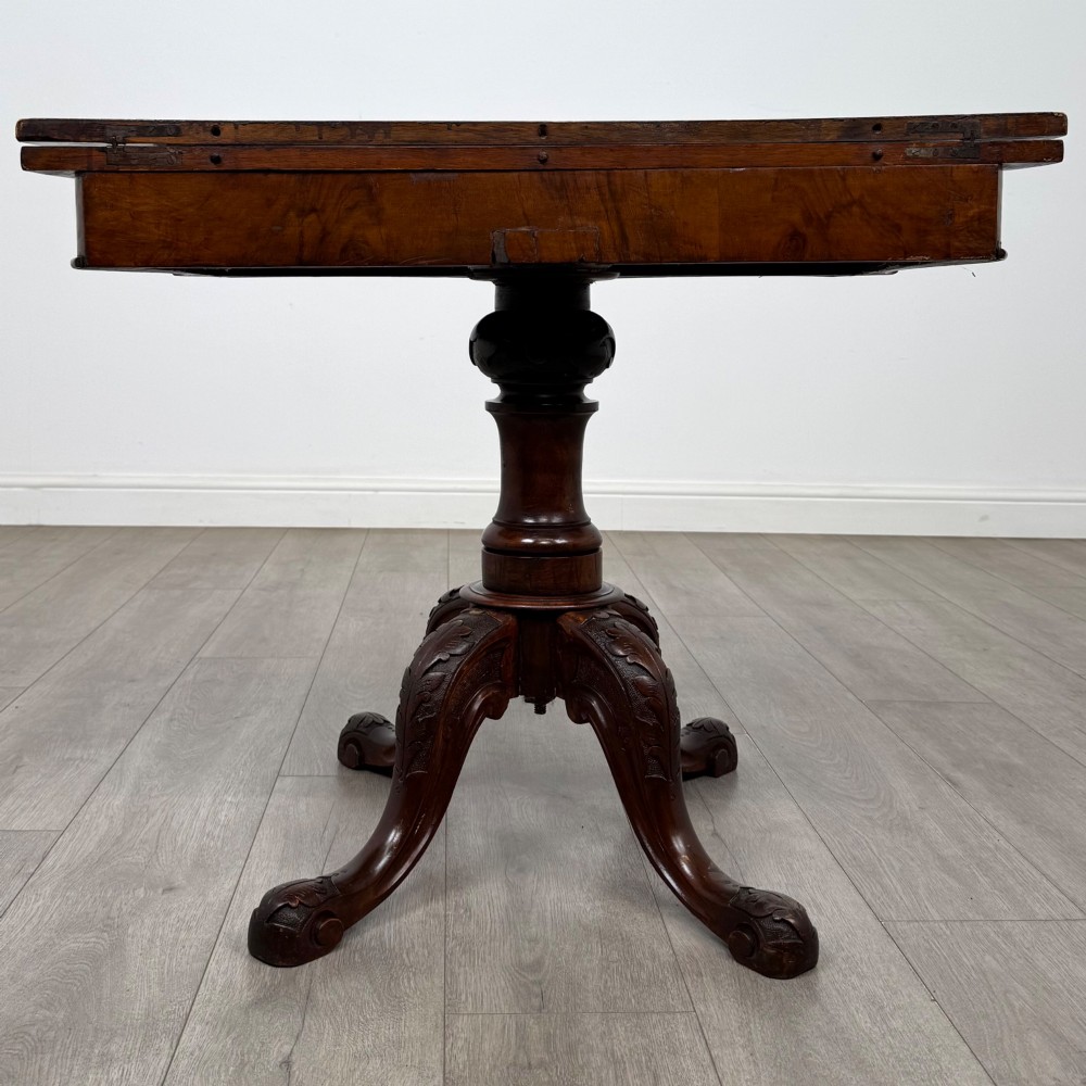 A 19th-century Victorian tea table in figured walnut, showcasing a carved rim, deep apron, turned pedestal, and four acanthus-carved scroll legs. View V