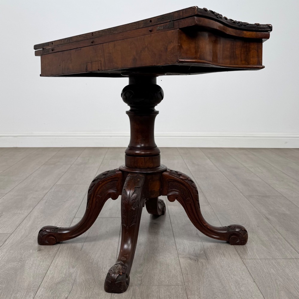 A 19th-century Victorian tea table in figured walnut, showcasing a carved rim, deep apron, turned pedestal, and four acanthus-carved scroll legs. View VI