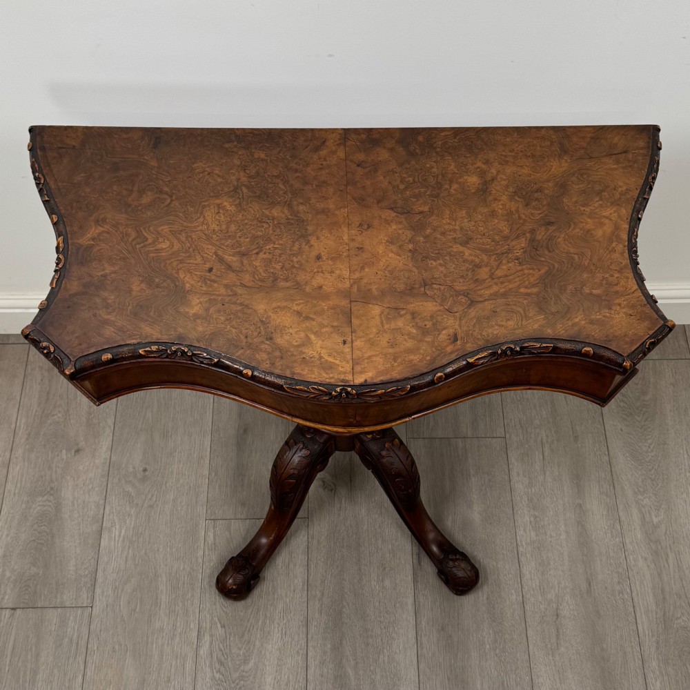 A 19th-century Victorian tea table in figured walnut, showcasing a carved rim, deep apron, turned pedestal, and four acanthus-carved scroll legs. View IX
