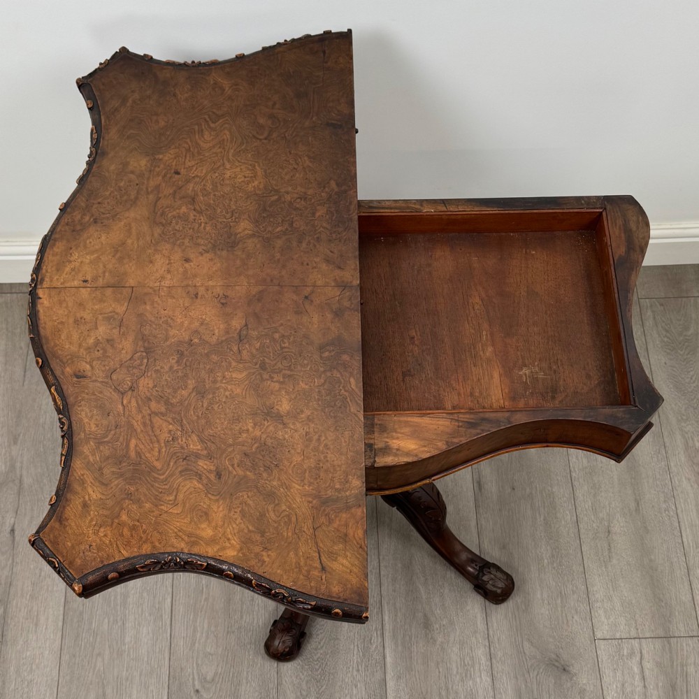 A 19th-century Victorian tea table in figured walnut, showcasing a carved rim, deep apron, turned pedestal, and four acanthus-carved scroll legs. View X