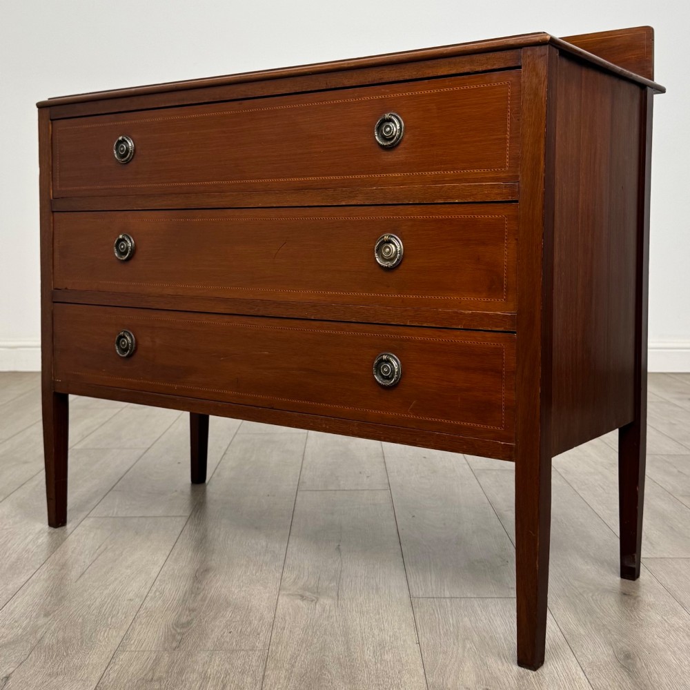 A 20th-century mahogany chest of drawers featuring three straight drawers with string inlay borders, brass ring handles, and square tapered legs. View II