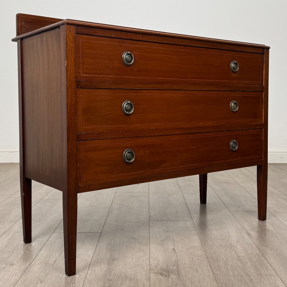 A 20th-century mahogany chest of drawers featuring three straight drawers with string inlay borders, brass ring handles, and square tapered legs. View VIII