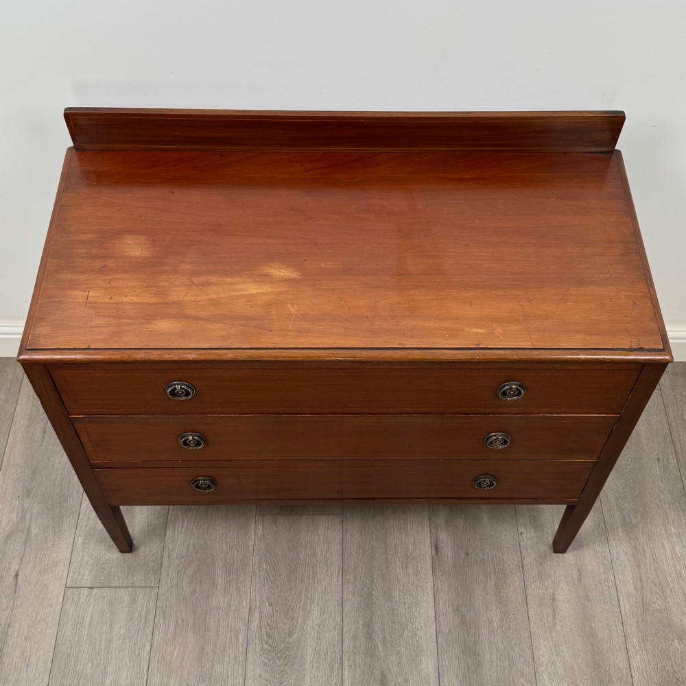 A 20th-century mahogany chest of drawers featuring three straight drawers with string inlay borders, brass ring handles, and square tapered legs. View IX