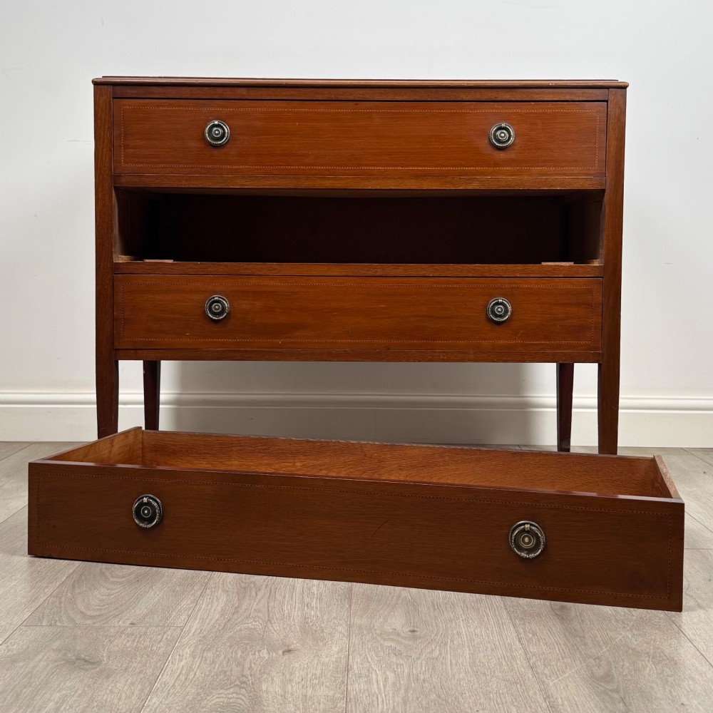A 20th-century mahogany chest of drawers featuring three straight drawers with string inlay borders, brass ring handles, and square tapered legs. View X
