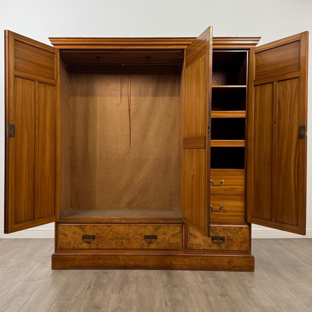 A large Art Deco burr walnut triple wardrobe featuring a central mirror door flanked by two panelled doors over base drawers. View II