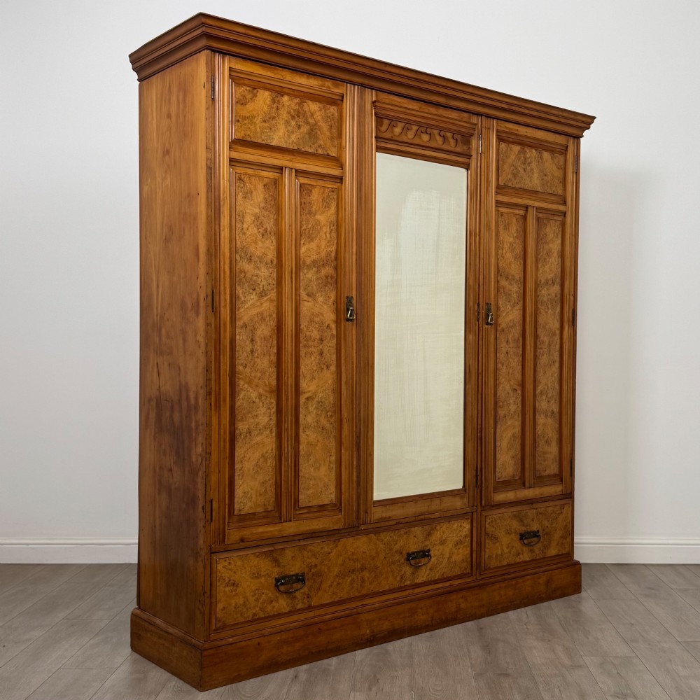 A large Art Deco burr walnut triple wardrobe featuring a central mirror door flanked by two panelled doors over base drawers. View IX