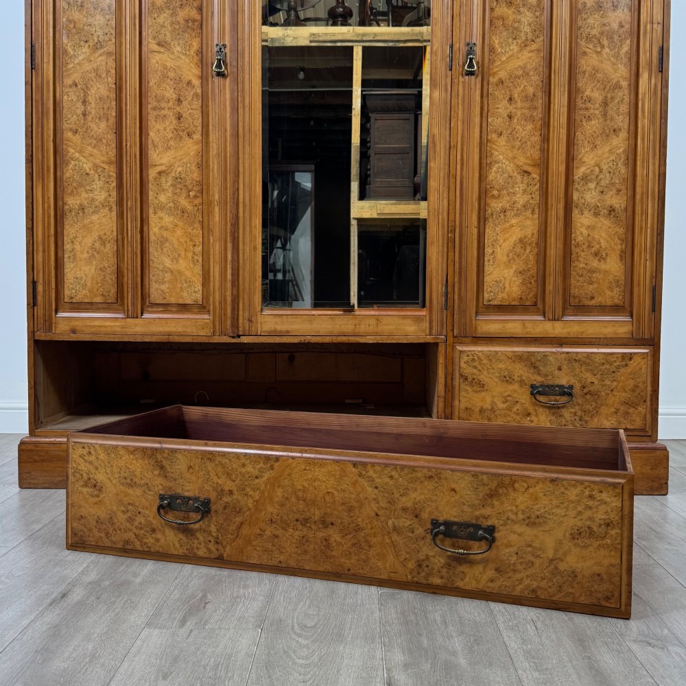 A large Art Deco burr walnut triple wardrobe featuring a central mirror door flanked by two panelled doors over base drawers. View X