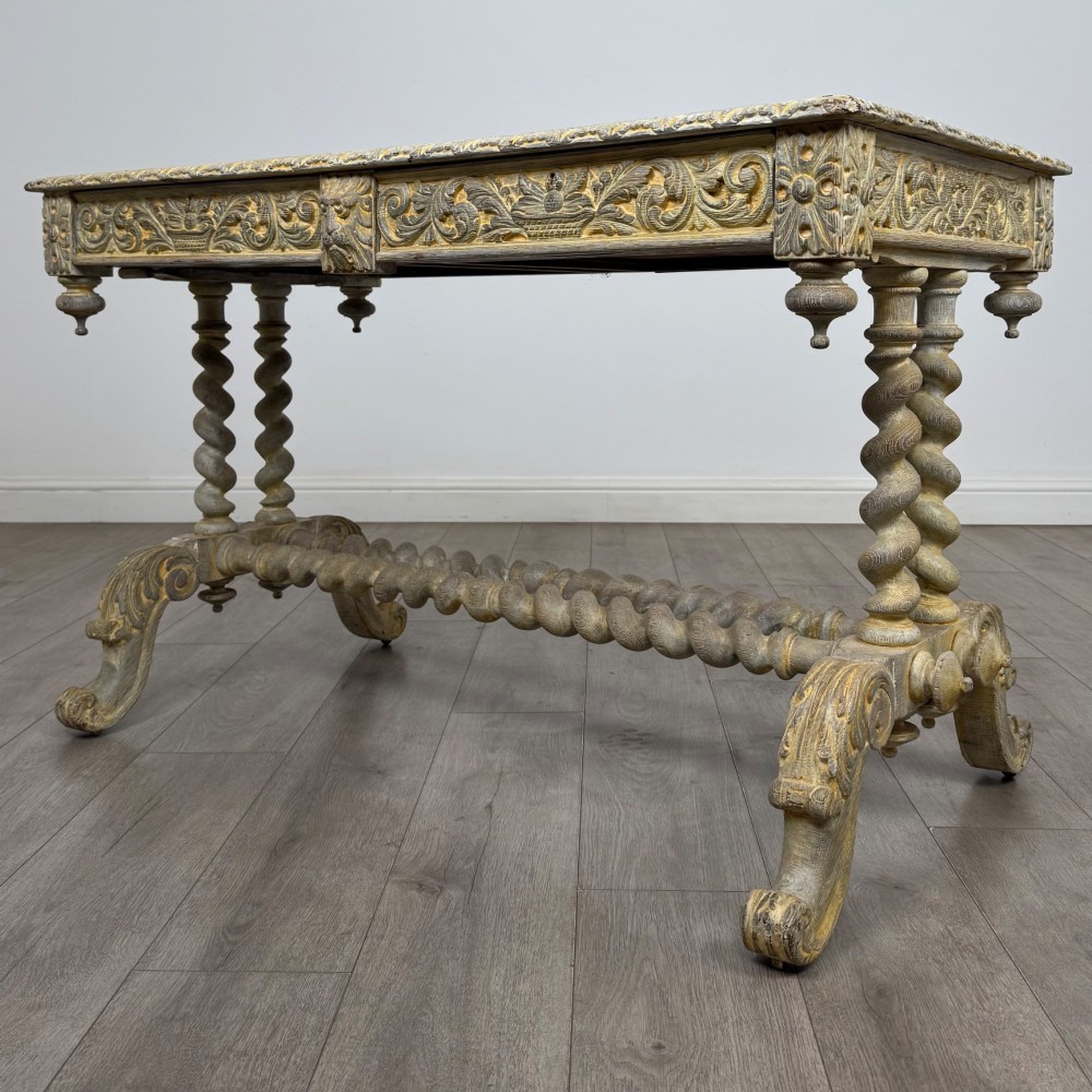 A 19th-century carved oak writing table with spiral barley-twist legs, foliage carving on the drawer frieze, and a weathered grey finish. View II