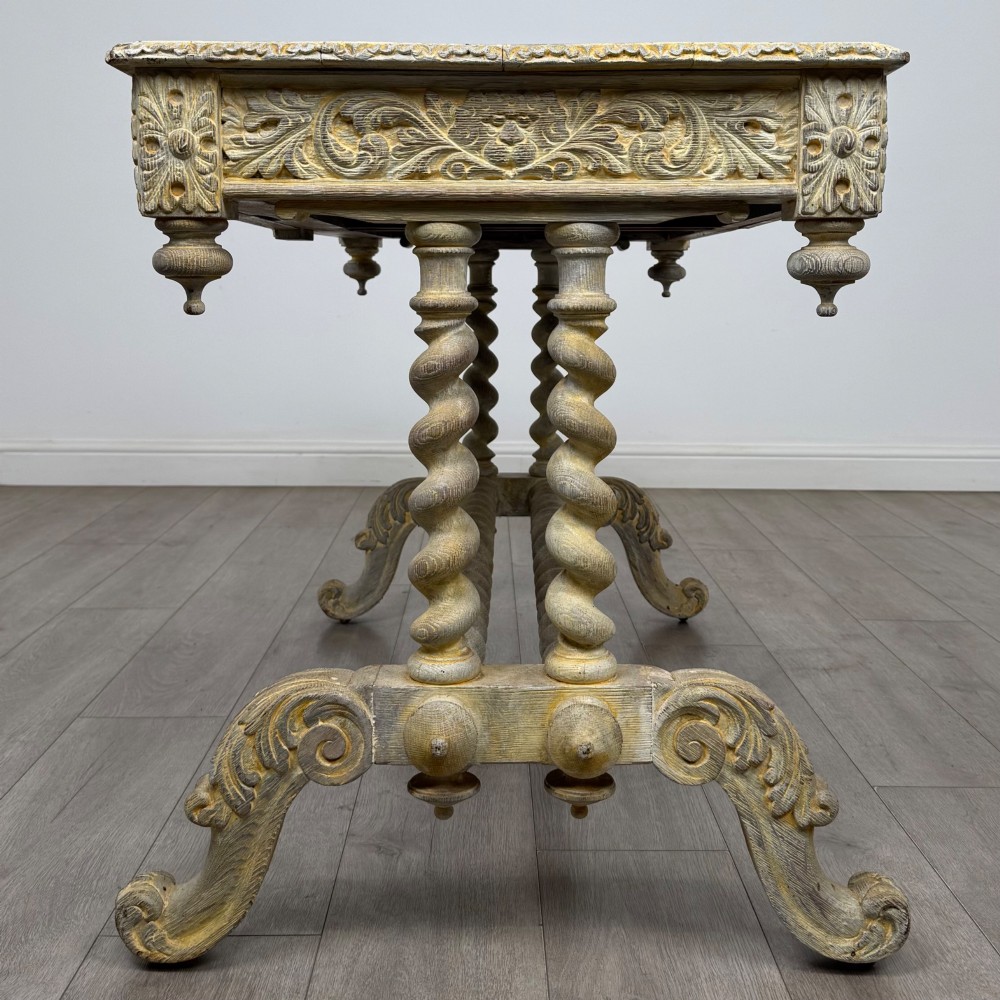 A 19th-century carved oak writing table with spiral barley-twist legs, foliage carving on the drawer frieze, and a weathered grey finish. View III