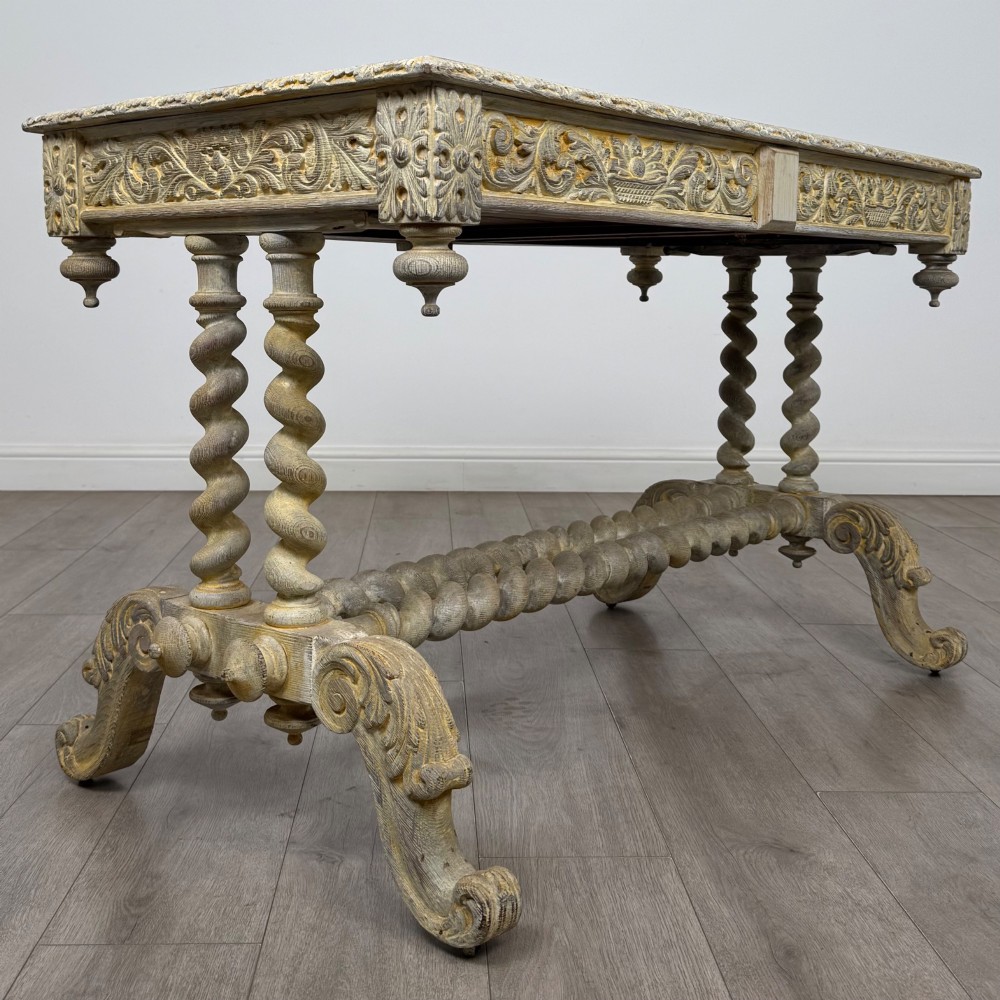 A 19th-century carved oak writing table with spiral barley-twist legs, foliage carving on the drawer frieze, and a weathered grey finish. View IV