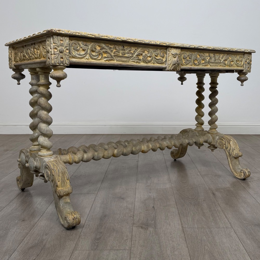A 19th-century carved oak writing table with spiral barley-twist legs, foliage carving on the drawer frieze, and a weathered grey finish. View VIII