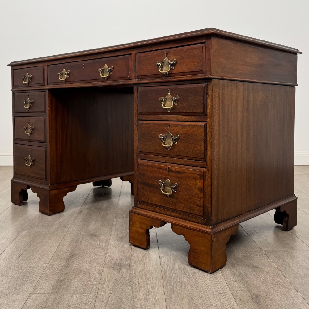 A 20th-century mahogany twin pedestal desk featuring nine drawers with brass drop handles and bracket feet. View II
