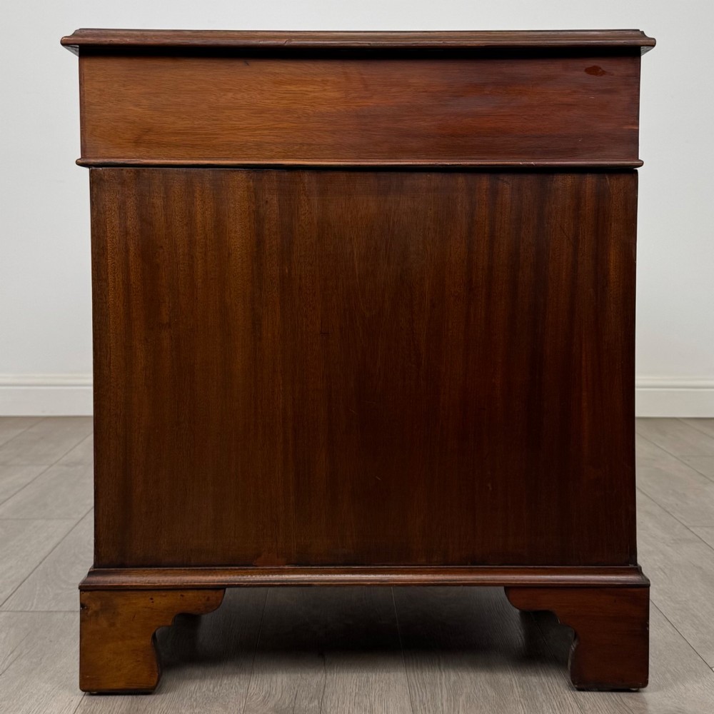 A 20th-century mahogany twin pedestal desk featuring nine drawers with brass drop handles and bracket feet. View III