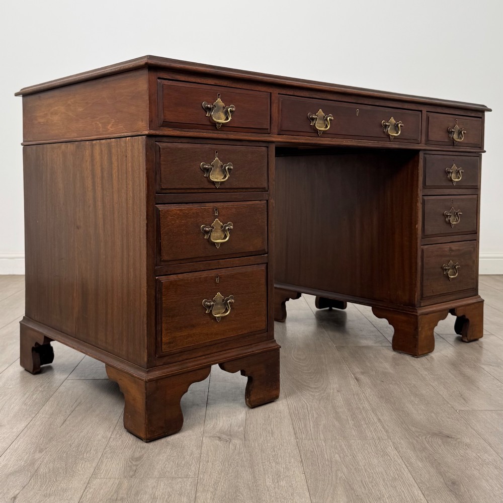 A 20th-century mahogany twin pedestal desk featuring nine drawers with brass drop handles and bracket feet. View VIII