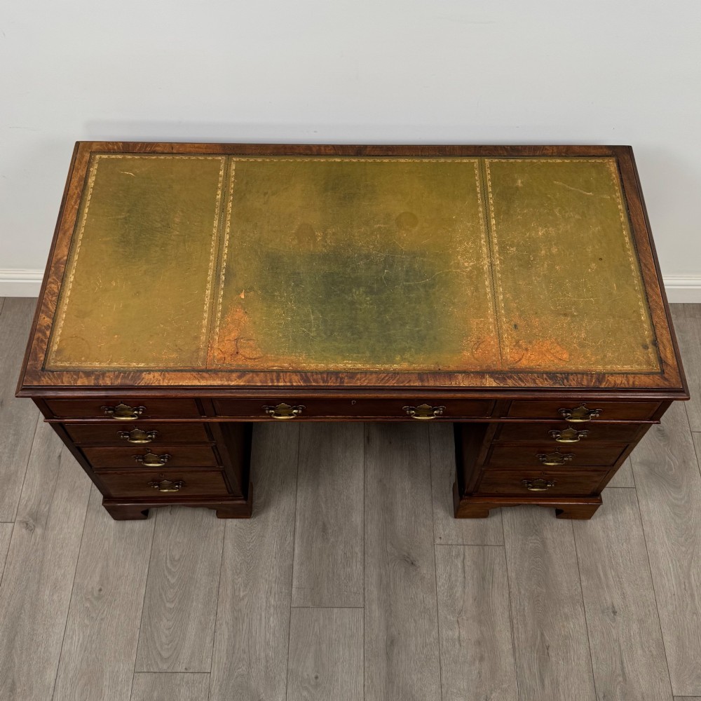A 20th-century mahogany twin pedestal desk featuring nine drawers with brass drop handles and bracket feet. View IX