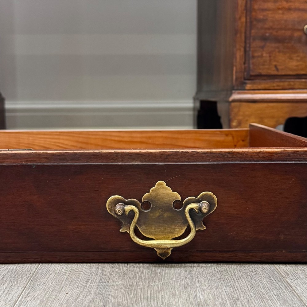 A 20th-century mahogany twin pedestal desk featuring nine drawers with brass drop handles and bracket feet. View XI