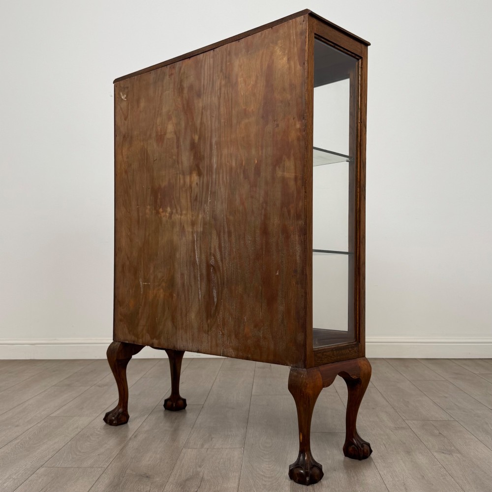 An antique 20th-century oak display cabinet featuring twin glazed doors, glass interior shelves, a carved top frieze, and cabriole legs ending in ball-and-claw feet. View VIII