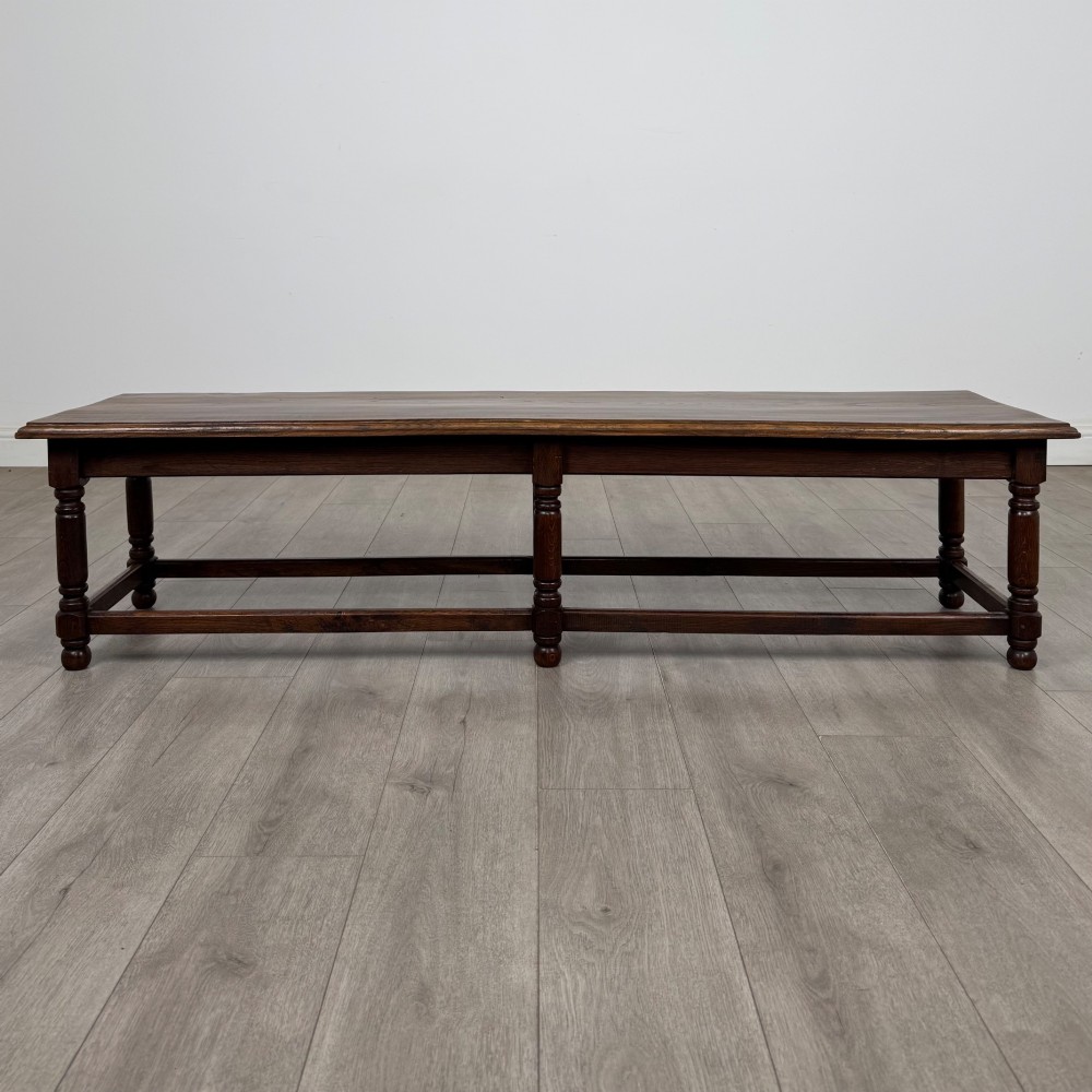 A long dark oak bench featuring six turned legs, perimeter stretchers, and a multi-coloured striped upholstered seat cushion. View II