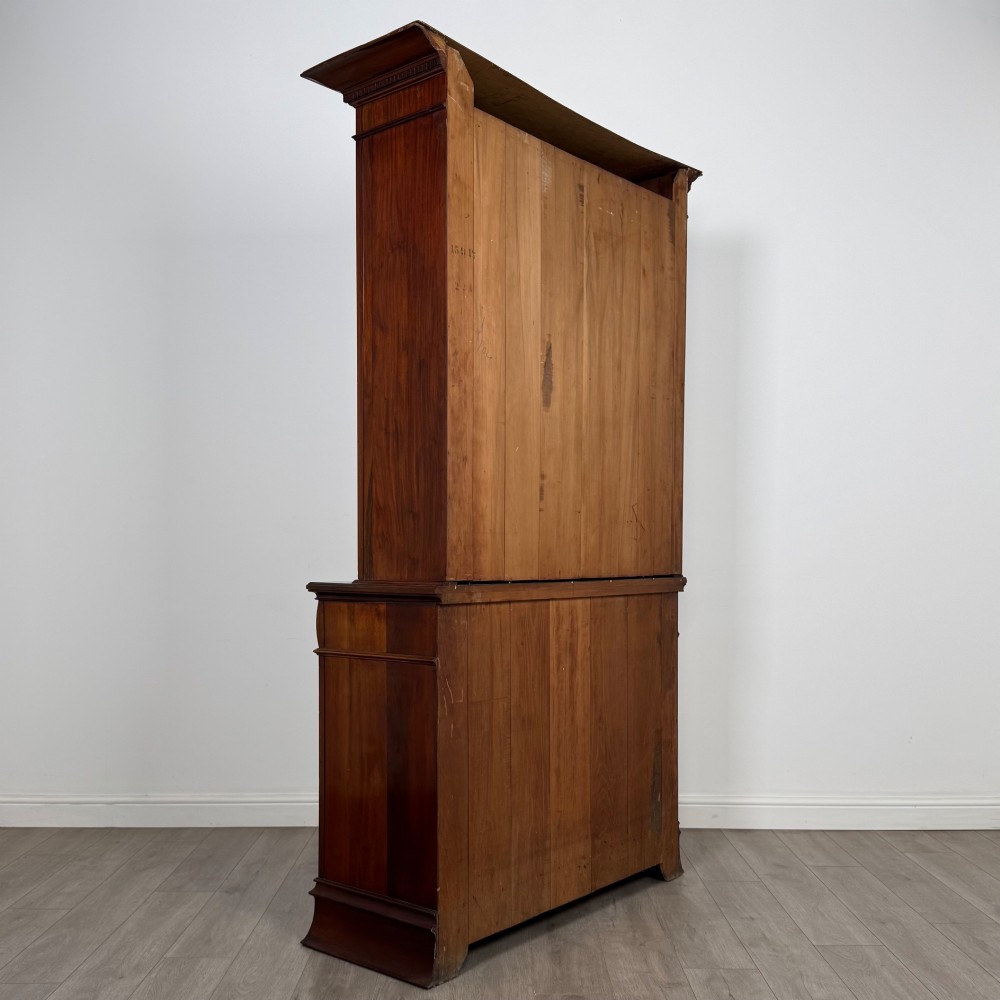An antique 20th-century mahogany glazed bookcase featuring two upper glass doors, twin middle drawers, and carved lower cupboard doors. View VI