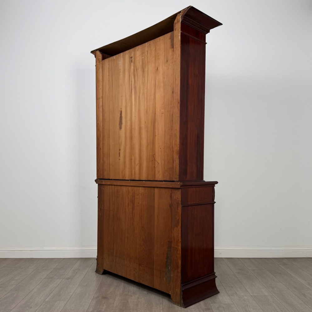 An antique 20th-century mahogany glazed bookcase featuring two upper glass doors, twin middle drawers, and carved lower cupboard doors. View VIII