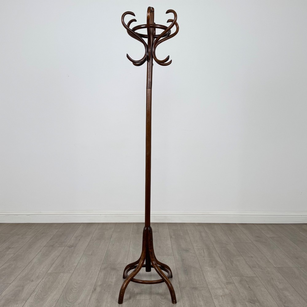 A tall dark brown beech bentwood coat stand featuring multiple curved hooks at the top and a circular quadruped base.