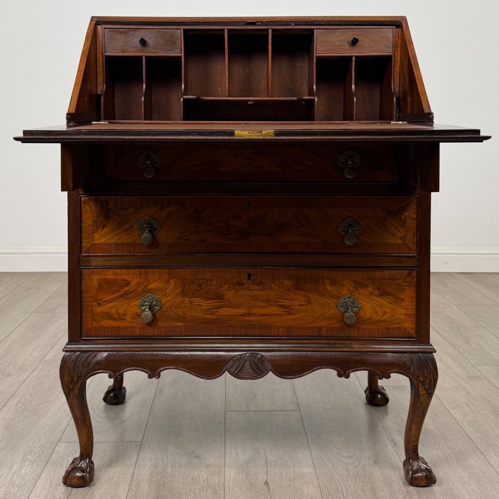 An antique Edwardian figured walnut writing bureau with a slant-front lid, three long drawers, brass handles, and carved cabriole legs on claw-and-ball feet. View II