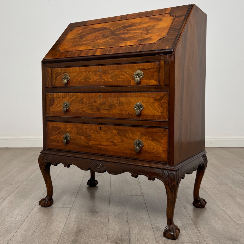 An antique Edwardian figured walnut writing bureau with a slant-front lid, three long drawers, brass handles, and carved cabriole legs on claw-and-ball feet. View III