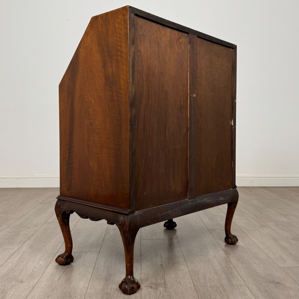 An antique Edwardian figured walnut writing bureau with a slant-front lid, three long drawers, brass handles, and carved cabriole legs on claw-and-ball feet. View V