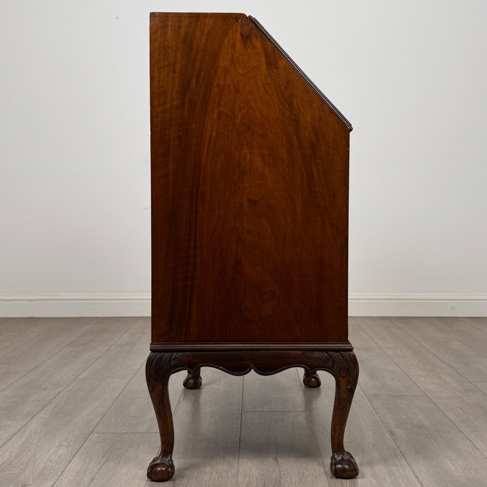 An antique Edwardian figured walnut writing bureau with a slant-front lid, three long drawers, brass handles, and carved cabriole legs on claw-and-ball feet. View VIII