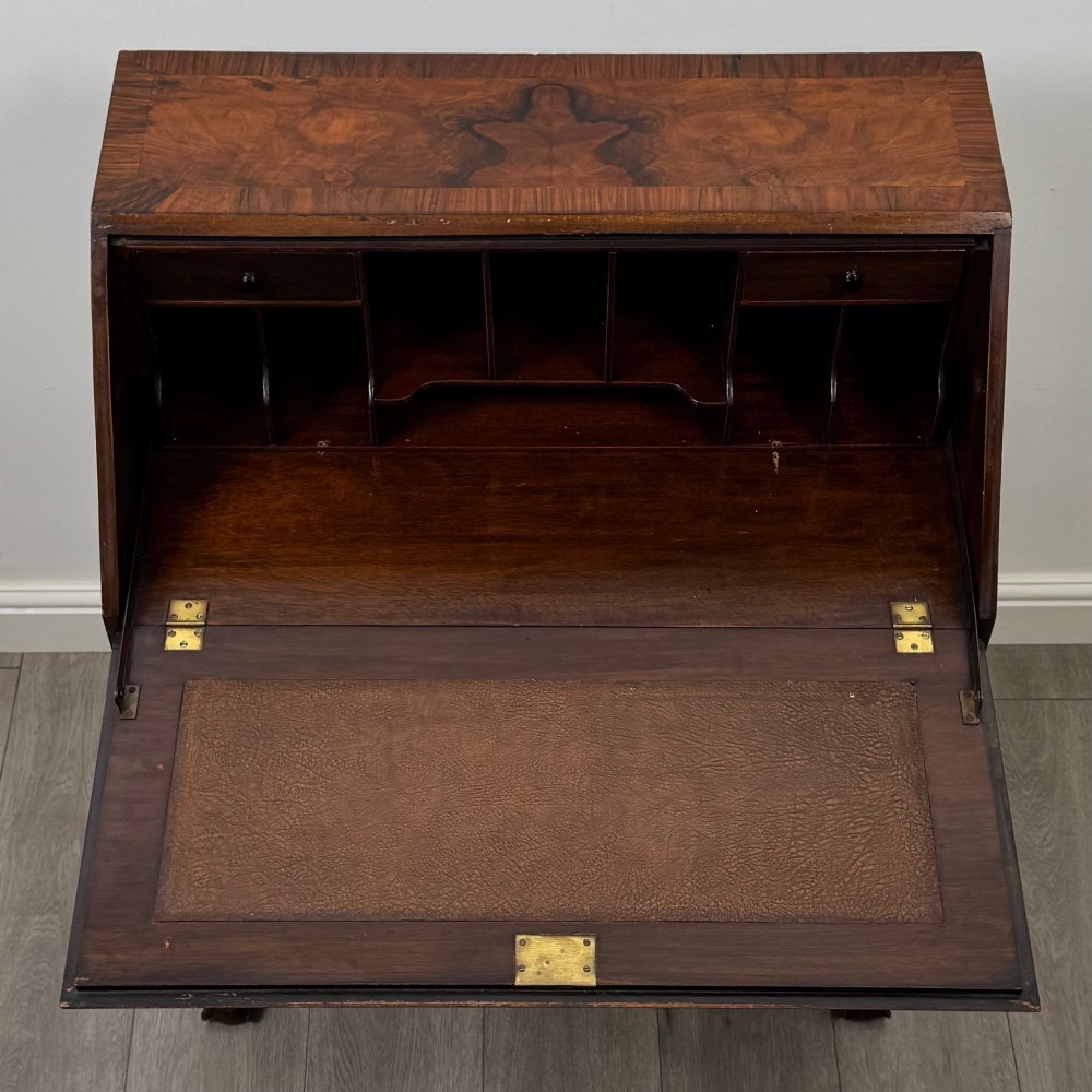 An antique Edwardian figured walnut writing bureau with a slant-front lid, three long drawers, brass handles, and carved cabriole legs on claw-and-ball feet. View XI
