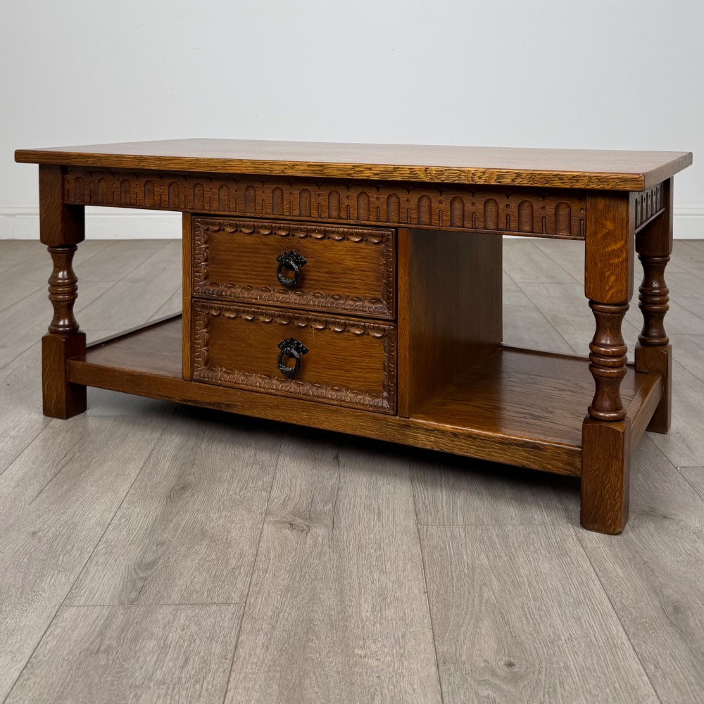 A rectangular carved oak coffee table with two central drawers, metal drop handles, turned legs, and a lower shelf. View II