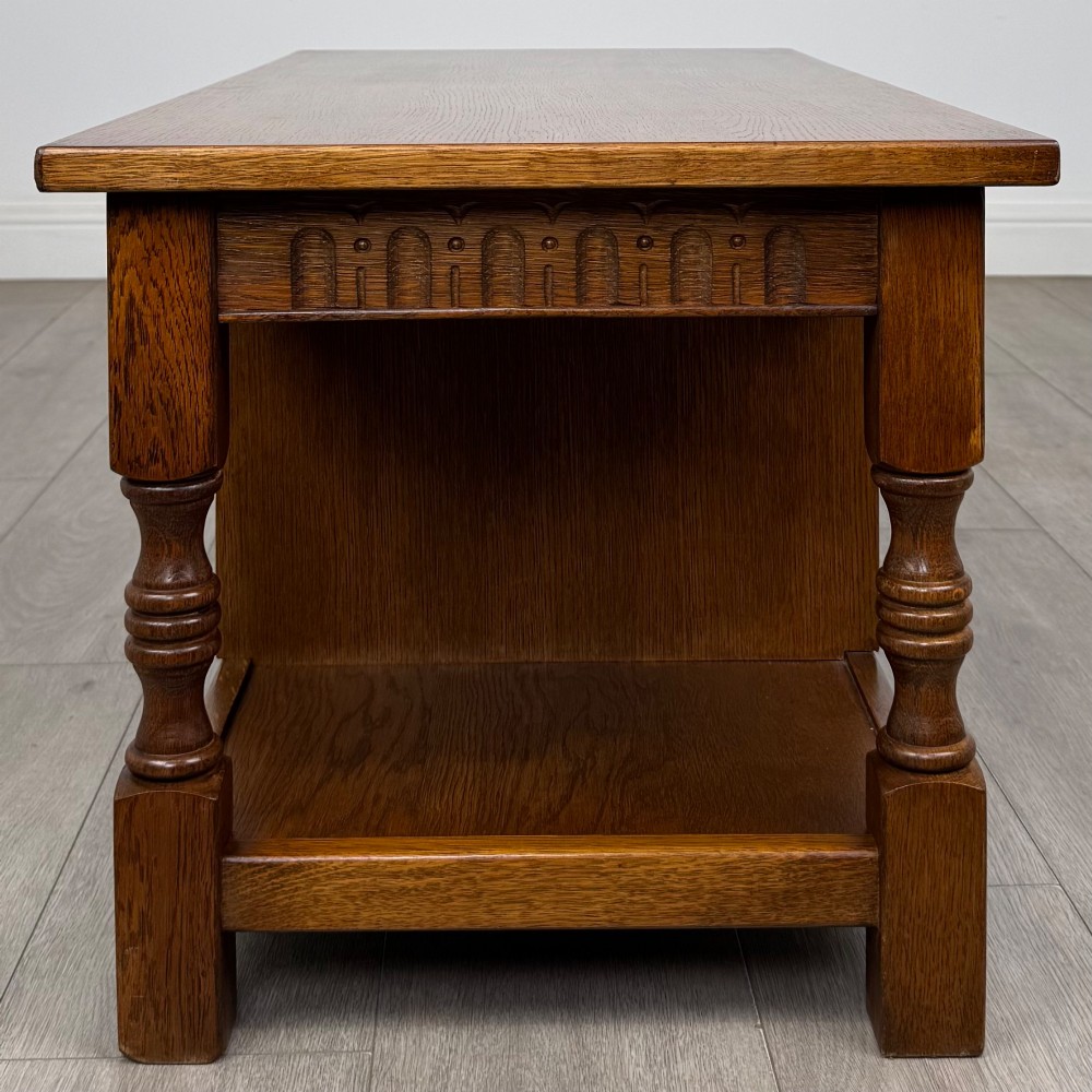 A rectangular carved oak coffee table with two central drawers, metal drop handles, turned legs, and a lower shelf. View III
