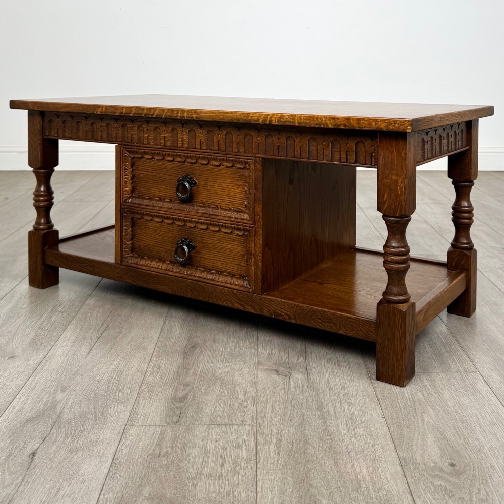 A rectangular carved oak coffee table with two central drawers, metal drop handles, turned legs, and a lower shelf. View VI