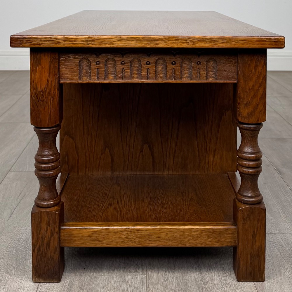 A rectangular carved oak coffee table with two central drawers, metal drop handles, turned legs, and a lower shelf. View VII