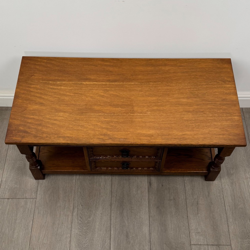 A rectangular carved oak coffee table with two central drawers, metal drop handles, turned legs, and a lower shelf. View IX