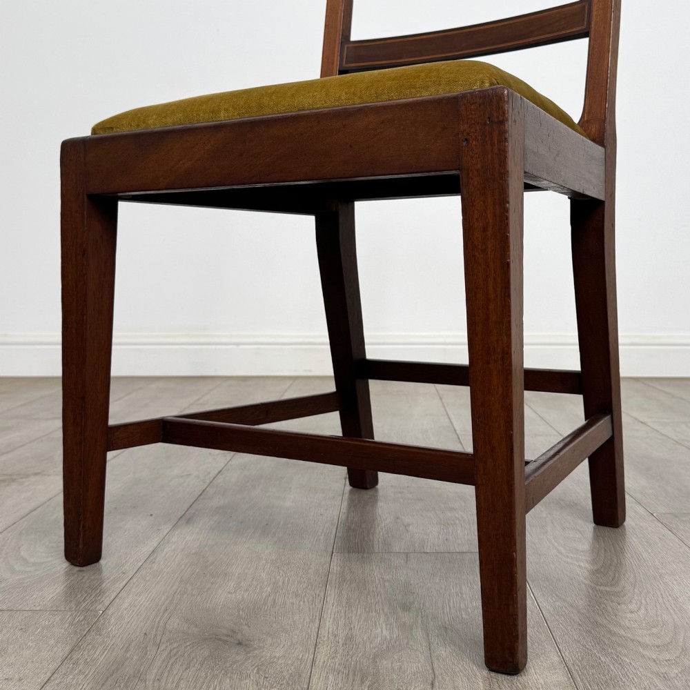 A set of six Georgian mahogany dining chairs featuring open rectangular backs with inlaid urn panels, straight legs with stretchers, and olive green velvet seats. View V