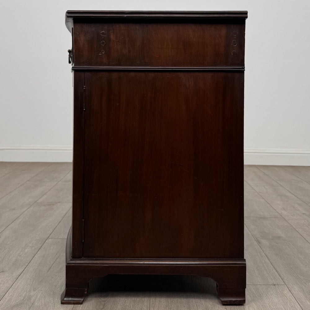 An antique Edwardian mahogany bow-front cupboard featuring two upper drawers with brass handles and two lower doors with oval wood grain panels. View IV