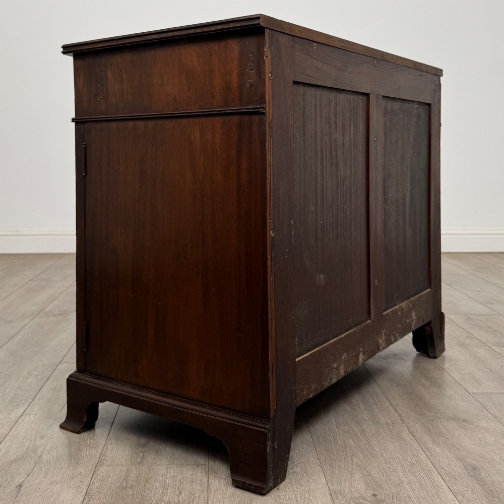 An antique Edwardian mahogany bow-front cupboard featuring two upper drawers with brass handles and two lower doors with oval wood grain panels. View V