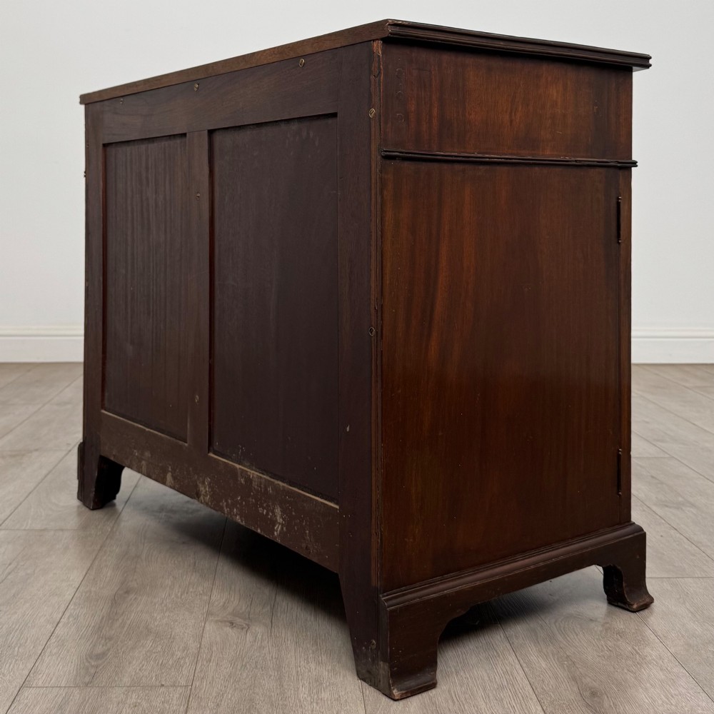 An antique Edwardian mahogany bow-front cupboard featuring two upper drawers with brass handles and two lower doors with oval wood grain panels. View VII