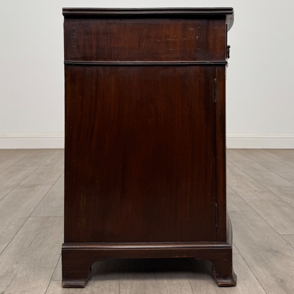 An antique Edwardian mahogany bow-front cupboard featuring two upper drawers with brass handles and two lower doors with oval wood grain panels. View VIII