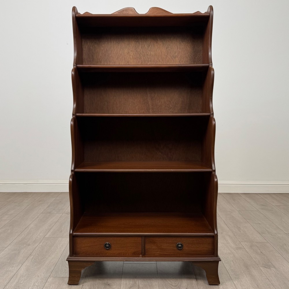 A freestanding dark mahogany waterfall bookcase with four graduated open shelves above two base drawers featuring ring pull handles. View II