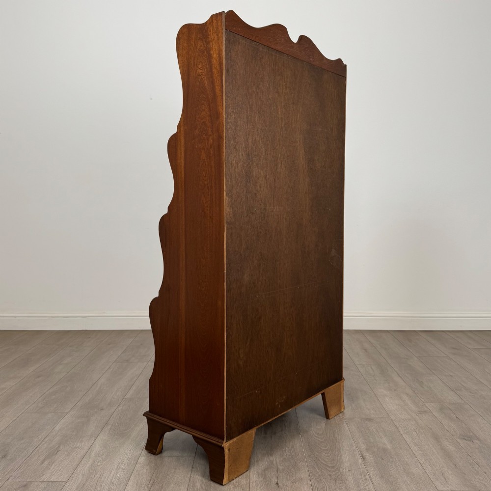 A freestanding dark mahogany waterfall bookcase with four graduated open shelves above two base drawers featuring ring pull handles. View V