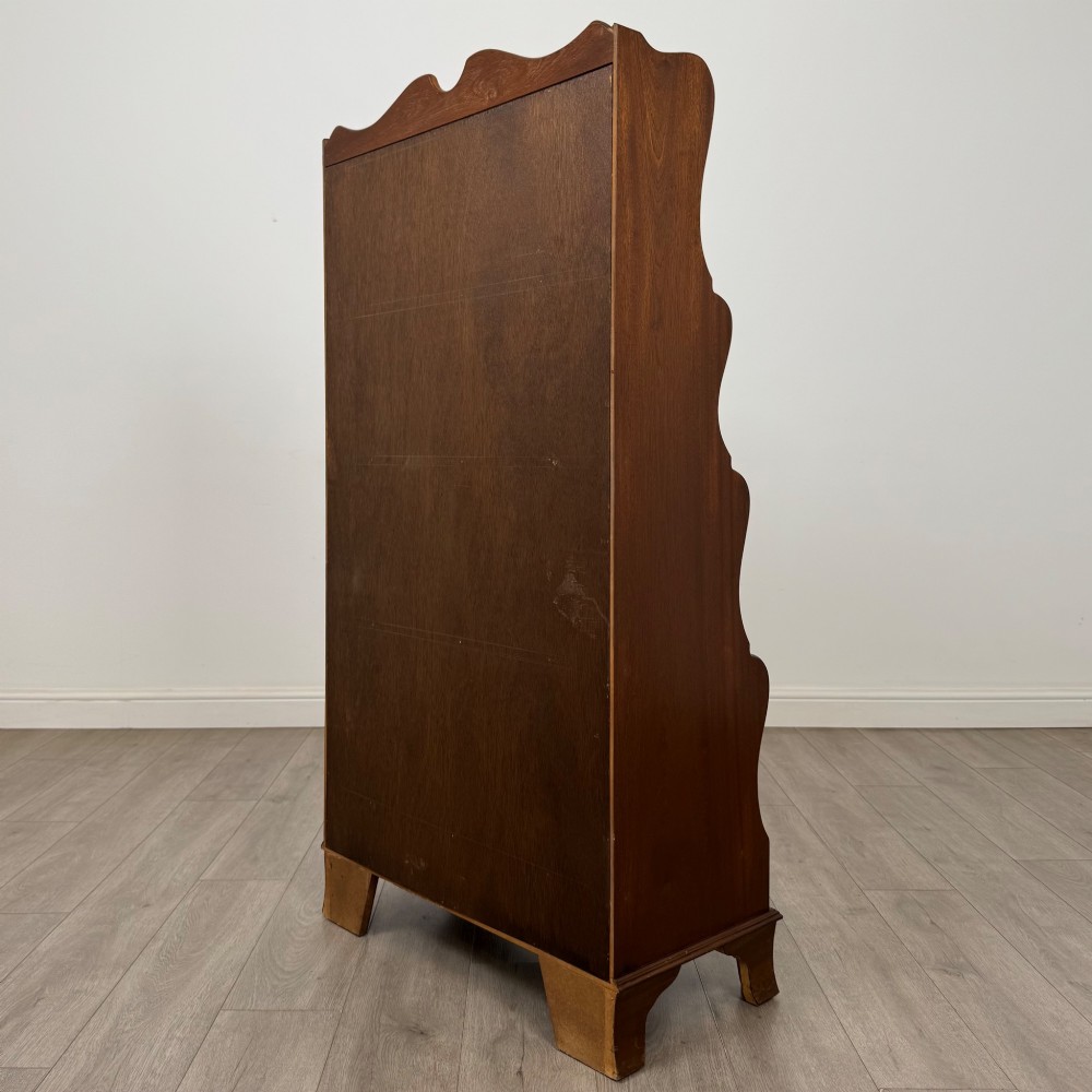 A freestanding dark mahogany waterfall bookcase with four graduated open shelves above two base drawers featuring ring pull handles. View VII