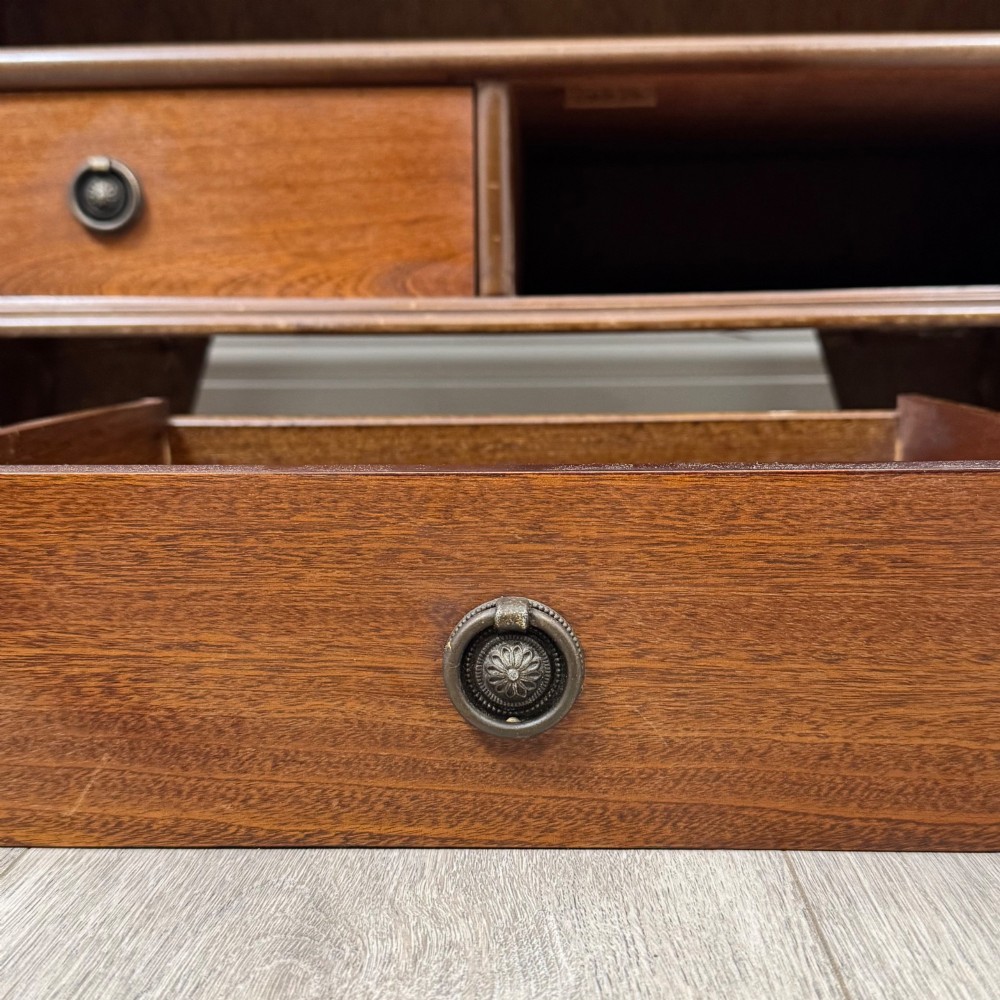 A freestanding dark mahogany waterfall bookcase with four graduated open shelves above two base drawers featuring ring pull handles. View XII