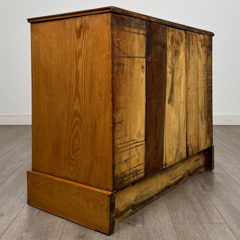 An antique Victorian oak chest of drawers featuring two short top drawers over two long lower drawers with dark drawer fronts, brass oval handles, and a plinth base. View IV
