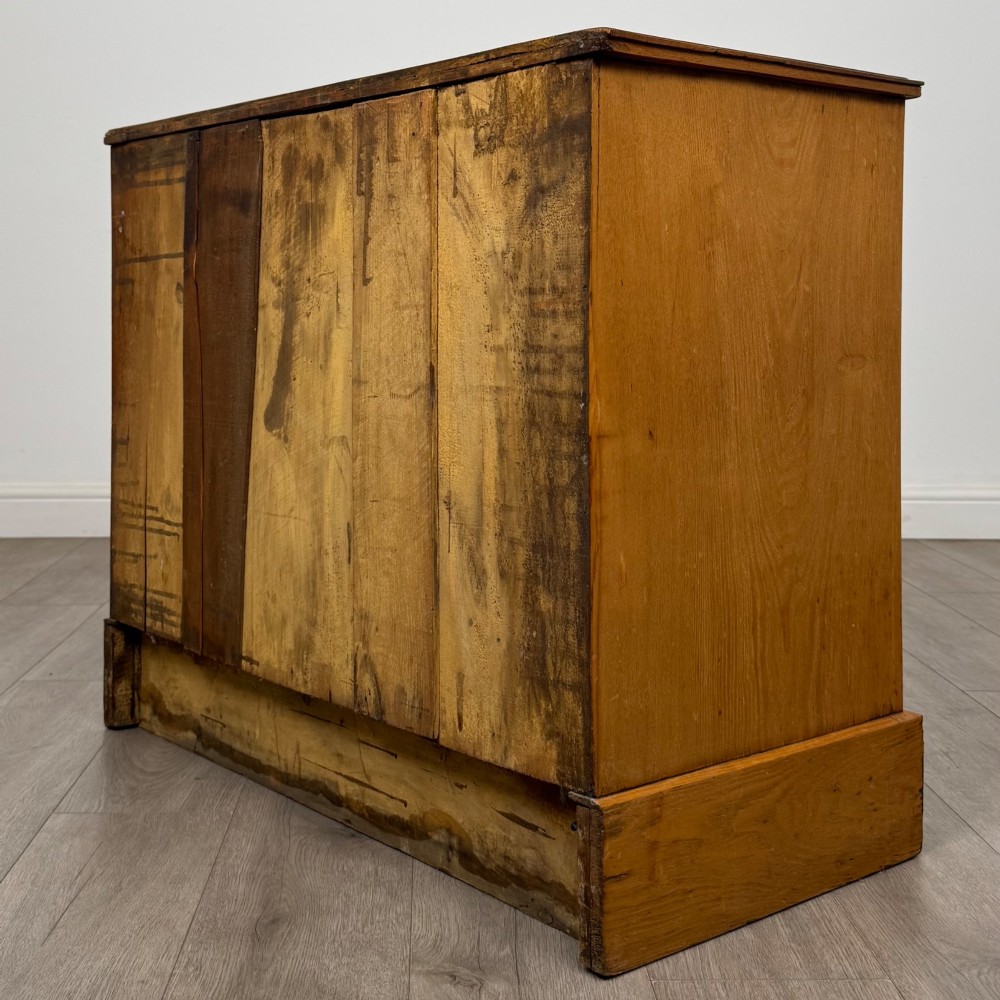An antique Victorian oak chest of drawers featuring two short top drawers over two long lower drawers with dark drawer fronts, brass oval handles, and a plinth base. View VI