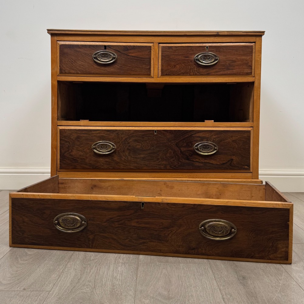 An antique Victorian oak chest of drawers featuring two short top drawers over two long lower drawers with dark drawer fronts, brass oval handles, and a plinth base. View X