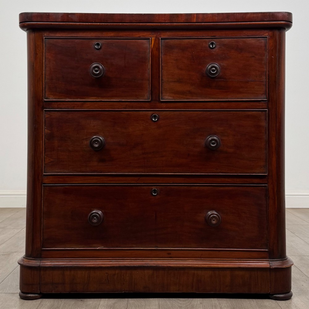 A Victorian dark mahogany chest of drawers featuring two short drawers above two full-width long drawers with turned wooden knobs and a solid plinth base.