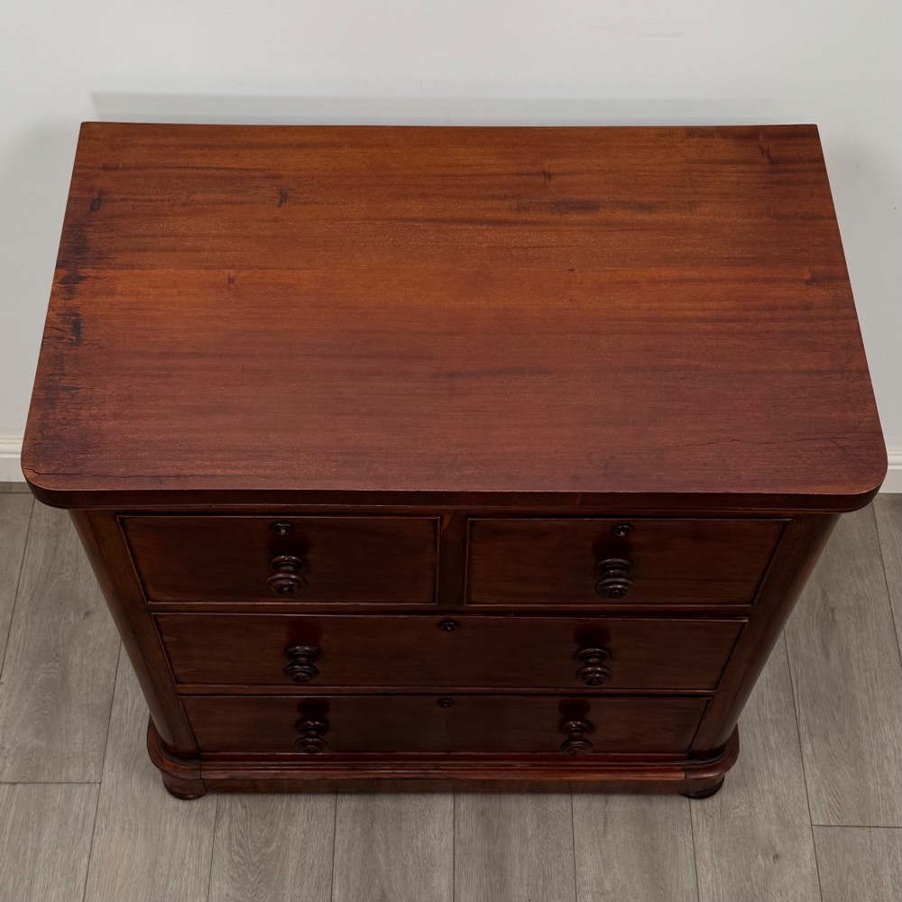 A Victorian dark mahogany chest of drawers featuring two short drawers above two full-width long drawers with turned wooden knobs and a solid plinth base. View IX